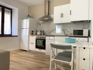 a kitchen with white cabinets and a table with a chair at Casa de los Canteros in Toledo