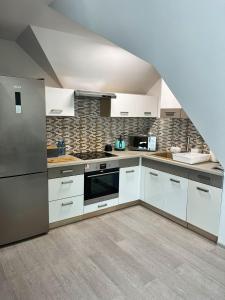 a large kitchen with white cabinets and appliances at Apartamenty Lumax in Gryfice