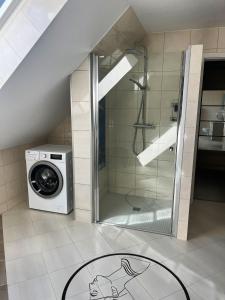 a bathroom with a shower and a washing machine at Apartamenty Lumax in Gryfice