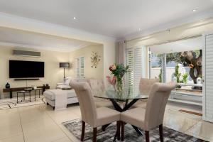 uma sala de estar com uma mesa de vidro e cadeiras em The Tram Home Stay em Franschhoek