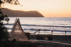 uma tenda sentada na praia ao pôr do sol em Conrad Punta de Mita em Punta Mita