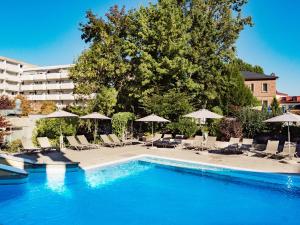 uma piscina com cadeiras e guarda-sóis ao lado de um hotel em Hotel Frankenland em Bad Kissingen