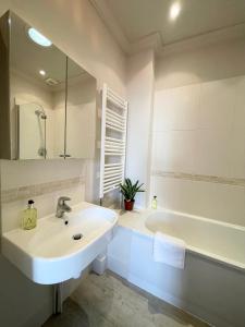 a white bathroom with a sink and a bath tub at Victoria Maisonette Apartment in London