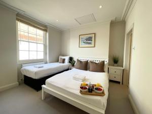 een slaapkamer met 2 bedden en een dienblad met fruit erop bij Victoria Maisonette Apartment in Londen