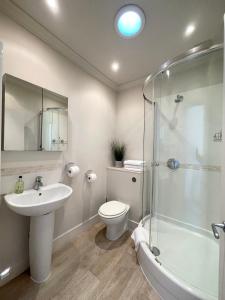 a bathroom with a sink and a toilet and a shower at Victoria Maisonette Apartment in London