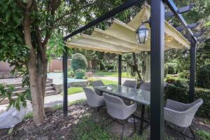 un patio avec une table et des chaises sous un parasol dans l'établissement Chamber’ 64 private pool villa, à Chiang Mai