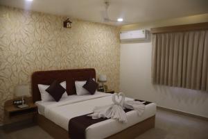a bedroom with a bed with a bow on it at The Sky Comfort Beach Hotel, Dwarka in Dwarka