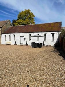 a white building with a picnic table in front of it at The Old Hay Barn - Games Room, Gym, Sleeps 8 in Godmanchester
