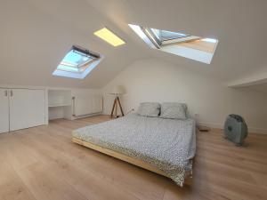 ein Schlafzimmer mit einem Bett in einem Zimmer mit Oberlichtern in der Unterkunft La Violeta - agréable maison jardin RER B - Metro 4 in Arcueil