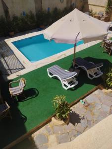 2 sillas y sombrilla junto a la piscina en فيلا بيجو en Tunis