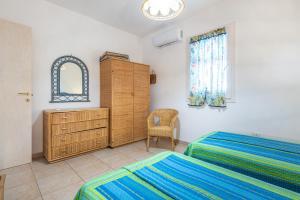 a bedroom with two beds and a dresser and a window at Sottotorre 1 in Calasetta