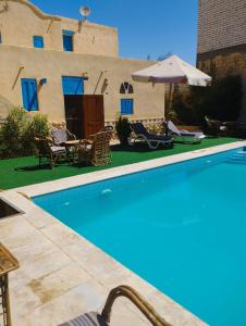 a pool in front of a house with an umbrella at فيلا بيجو in Tunis
