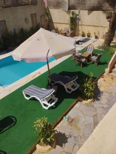 a group of lawn chairs and an umbrella next to a pool at فيلا بيجو in Tunis