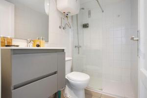 a white bathroom with a toilet and a shower at Piso Relax - Carpe Mundi in Corralejo +16 photos