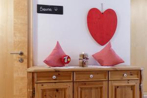 a wooden cabinet with pink pillows and a heart on the wall at Apartments Gannerhof in Obertilliach