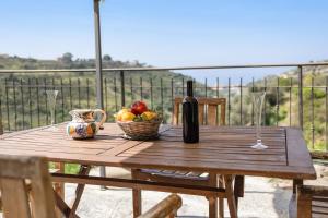 un tavolo in legno con cesto di frutta e bottiglia di vino di Pelagos a Pompeiana