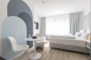 a bedroom with a bed and a table and a chair at zzzpace Smart-Hotel Bielefeld Zentrum in Bielefeld