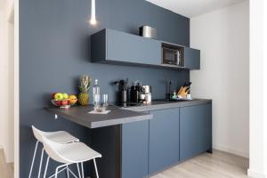 a kitchen with a blue wall with a counter top at zzzpace Smart-Hotel Bielefeld Zentrum in Bielefeld