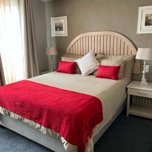 a bedroom with a large bed with red pillows at Cape Town Beachfront Apartments at Leisure Bay in Cape Town
