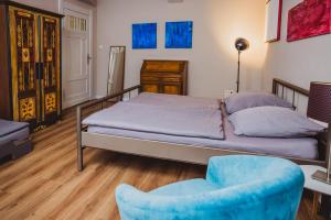 ein Schlafzimmer mit einem Bett und einem blauen Stuhl in der Unterkunft Charmanter Altbau zwischen Altstadt und Klinikum mit Parkplatz in Greifswald