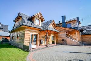 a wooden house with a gambrel roof at Apartament & Domek u Gabrysi in Białka Tatrzanska