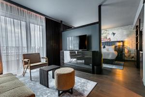 ein Wohnzimmer mit einem Sofa, einem Bett und einem TV in der Unterkunft NYX Hotel Hamburg by Leonardo Hotels in Hamburg