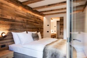 a bedroom with a wooden accent wall and a bed at K Lodge in Valdaora