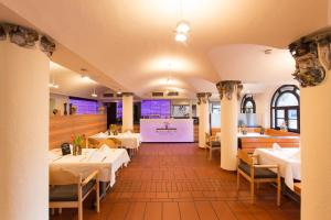uma sala de jantar com mesas e cadeiras brancas em Herzogskelter Restaurant Hotel em Güglingen