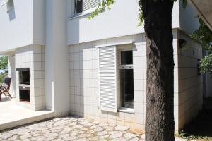 ein weißes Haus mit einem Fenster und einem Baum in der Unterkunft Apartments PineWood Villa in Krk
