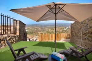 a patio with two chairs and an umbrella at Villa Esperanza in La Cisnera