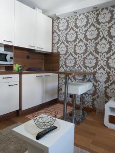 uma cozinha com armários brancos e um controle remoto sobre uma mesa em MR. O Apartments Kopaonik em Kopaonik