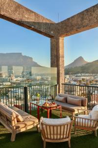 a balcony with chairs and tables and a view of a city at The Silo Hotel in Cape Town