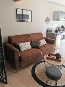 a brown leather couch in a living room with a table at Chaleureux Studio de 35m2 totalement indépendant in Fors