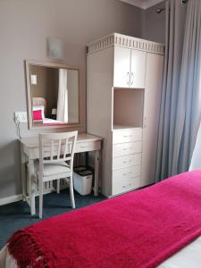 a bedroom with a vanity and a desk with a mirror at Cape Town Beachfront Apartments at Leisure Bay in Cape Town