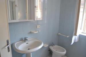 uma casa de banho branca com um lavatório e um WC em Appartamento 6 em Ameglia