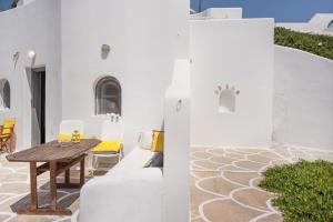 a patio with a wooden table and yellow chairs at Kimolos in Sikinos