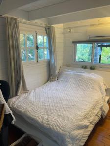 1 dormitorio con 1 cama blanca y 2 ventanas en בקתות עץ סקנדינביות במטולה, en Metula