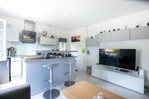 ein Wohnzimmer mit einer Küche mit einer Bar und einem TV in der Unterkunft Sable et Reflets - T2 - Centre ville d'Hossegor in Soorts-Hossegor