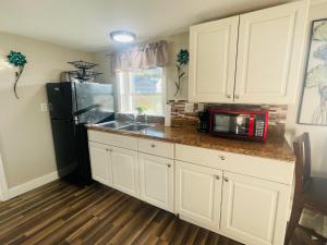 a kitchen with white cabinets and a black refrigerator at Studio Apt - Nottingham NH in Nottingham