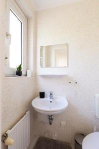 a white bathroom with a sink and a mirror at Perle am Maschsee. Ein Haus mit Garten und 4 Zimmern in Hannover