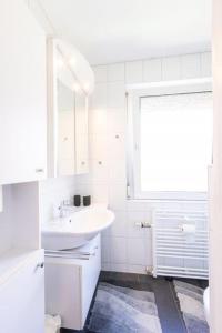 uma casa de banho branca com um lavatório e uma janela em Perle am Maschsee. Ein Haus mit Garten und 4 Zimmern em Hanôver
