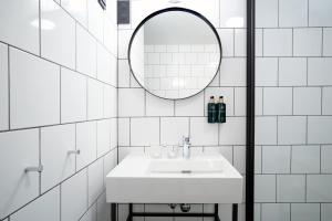ein weißes Badezimmer mit einem Waschbecken und einem Spiegel in der Unterkunft Clarion Collection Hotel Tollboden in Drammen