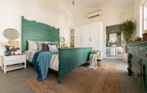 una camera da letto con un grande letto verde con testiera verde di LohonoStays Colina Villa C a Vagator