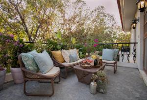 a patio with wicker chairs and tables and flowers at LohonoStays Colina Villa C in Vagator