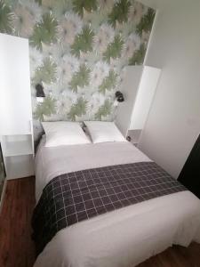 1 dormitorio con 1 cama y papel pintado con motivos florales en Le Tréville Grand Studio Cosy 32M2, en Rochefort