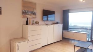 a living room with a white dresser and a tv at Studio met zeezicht in Blankenberge