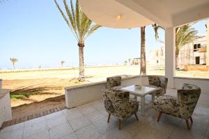 a patio with a table and chairs and a view of the beach at Beach house First Row sea view at Santa Monica next to Almaza Bay in Marsa Matruh