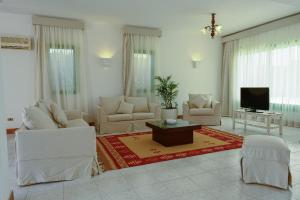 a living room with white furniture and a flat screen tv at Beach house First Row sea view at Santa Monica next to Almaza Bay in Marsa Matruh