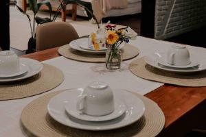 uma mesa com pratos, copos e flores em Casa de campo em Joinville com Hidromassagem e Lareira em Joinville