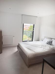 a white bedroom with a bed and a window at Lovely Charming 2-Bedroom Apartment in Bow London in London